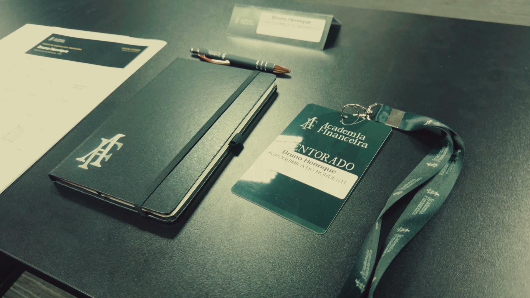 Material e crachá de mentorado da Academia Financeira sobre a mesa